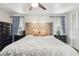 Bedroom with a large tufted headboard, bedside tables with lamps, and windows with decorative curtains at 10387 Majestic Dr, Largo, FL 33774