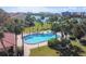 Community pool surrounded by palm trees and overlooking the water with lounge chairs and tables at 10387 Majestic Dr, Largo, FL 33774