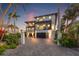 Contemporary two-story home with multiple balconies, a paved driveway, and lush tropical landscaping at 12400 Capri N Cir, Treasure Island, FL 33706