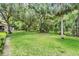 Expansive backyard featuring a lush green lawn, mature trees, and ample space for outdoor activities at 1400 Tarpon Woods Blvd # E4, Palm Harbor, FL 34685