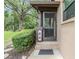 Close-up of a screen door entrance with tiled steps, framed by lush greenery for added privacy at 1400 Tarpon Woods Blvd # E4, Palm Harbor, FL 34685
