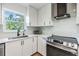 Close-up of a bright kitchen with white cabinets, a black faucet, and a view to the tropical backyard at 1400 Tarpon Woods Blvd # E4, Palm Harbor, FL 34685