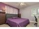 Bedroom boasts a large bed, purple accent wall with stylish curtains, and a bright window at 1403 W Pradera Ave, Tampa, FL 33612
