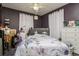 A messy bedroom features a grey headboard, purple walls, white curtains, and ceiling fan at 1403 W Pradera Ave, Tampa, FL 33612