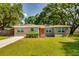 Charming single-story home featuring a well-manicured lawn, mature trees, and inviting curb appeal at 1403 W Pradera Ave, Tampa, FL 33612