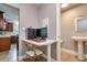 Small office space with computer setup next to a half-bathroom featuring a pedestal sink and tile flooring at 1403 W Pradera Ave, Tampa, FL 33612