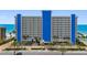 Bright and airy exterior shot of the condo building overlooking tropical landscaping and the ocean at 14950 Gulf Blvd # 905, Madeira Beach, FL 33708