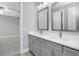 Bathroom featuring gray cabinets with double sinks, white countertops, and access to bedroom at 17404 Nokota Ave, Hudson, FL 34667