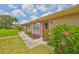 Charming condo with a well-manicured lawn, beautiful landscaping, and a red door, creating a welcoming entrance at 1904 Canterbury Ln # 18, Sun City Center, FL 33573
