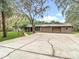 Charming ranch-style home with mature trees and a spacious driveway leading to an attached garage at 27315 Popiel Rd, Brooksville, FL 34602
