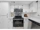 Kitchen featuring stainless steel appliances, including a stove and a microwave, with white countertops and cabinets at 3004 Conifer Dr, Largo, FL 33771
