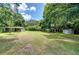 View of the backyard with a lawn, mature trees, and multiple shed structures at 38839 Miller Ave, Zephyrhills, FL 33542