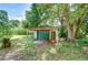 Exterior view of garage showcasing green doors and surrounding yard with mature trees at 38839 Miller Ave, Zephyrhills, FL 33542