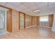 Living room featuring wood paneling, ceiling tiles and an open doorway at 38839 Miller Ave, Zephyrhills, FL 33542
