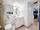 Bright bathroom featuring white vanity, medicine cabinet, neutral tile flooring, and a view of the kitchen at 4725 Cove Circle # 908, St Petersburg, FL 33708