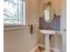 Bathroom with pedestal sink, decorative mirror, wood-look flooring and window at 504 Riverside Dr # 504, Tarpon Springs, FL 34689