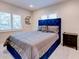 Comfortable bedroom with a plush blue bed, stylish nightstand, soft gray carpet, and bright natural light at 504 Riverside Dr # 504, Tarpon Springs, FL 34689