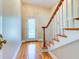 Bright foyer featuring hardwood floors, staircase with wood trim, and a decorative front door at 504 Riverside Dr # 504, Tarpon Springs, FL 34689
