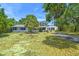Inviting single-story home with mature trees, a brick chimney, and a classic driveway and manicured lawn at 601 75Th St N, St Petersburg, FL 33710