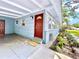 Charming covered entryway featuring a red front door, a 'welcome' mat, and well-maintained landscaping at 6700 14Th N St, St Petersburg, FL 33702