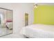 Bright bedroom with mirrored closet doors, white tile flooring, and a vibrant accent wall at 7833 Ontario Street Cir, Sarasota, FL 34243