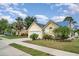 Charming yellow home featuring a well-manicured lawn, lush landscaping, and a paved driveway leading to an attached garage at 7833 Ontario Street Cir, Sarasota, FL 34243