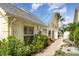 Charming home exterior with mature landscaping, including vibrant flowers and lush greenery along a brick walkway at 7833 Ontario Street Cir, Sarasota, FL 34243