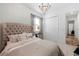 Bright bedroom with a tufted headboard, chandelier, and neutral decor at 7922 Lakes Edge Ln, Port Charlotte, FL 33981
