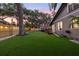 Artificial grass backyard featuring mature trees, wood fence, and a deck with a red umbrella at 1005 Main St, Safety Harbor, FL 34695