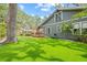 Backyard with a spacious lawn, lush trees, and a wooden deck with a red umbrella at 1005 Main St, Safety Harbor, FL 34695