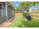 Charming backyard with artificial grass, wooden fence, brick pathway, and covered grill at 1005 Main St, Safety Harbor, FL 34695