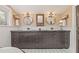 Bathroom features a dual sink vanity with custom cabinets, round mirrors and sconces at 1005 Main St, Safety Harbor, FL 34695