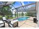 Screened-in pool with lake view, tiled deck, and comfortable outdoor seating for relaxing and entertaining at 10112 Downey Ln, Tampa, FL 33626