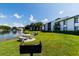 Lush green lawn next to a pond with outdoor seating areas for residents at 1109 Pine Ridge W Cir # C1, Tarpon Springs, FL 34688