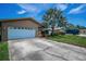 Single-story home featuring a large palm tree, landscaped front yard, driveway and a two-car garage at 1281 Amberlea E Dr, Dunedin, FL 34698