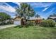 Charming single Gathering home with mature landscaping and a well-manicured lawn under a blue sky at 1281 Amberlea E Dr, Dunedin, FL 34698