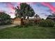 Charming single Gathering home with mature landscaping and a well-manicured lawn under a colorful sky at 1281 Amberlea E Dr, Dunedin, FL 34698