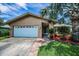 Single-story home featuring a large palm tree, landscaped front yard and a two-car garage at 1281 Amberlea E Dr, Dunedin, FL 34698