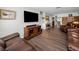Open-concept living room with hardwood floors, a large flat-screen television, and comfortable leather sofas at 1281 Amberlea E Dr, Dunedin, FL 34698
