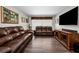Comfortable living room with hardwood floors, leather furniture, and a flat-screen television, perfect for relaxation at 1281 Amberlea E Dr, Dunedin, FL 34698