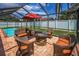 Enclosed patio with fire pit, outdoor seating, and views of the pool and backyard at 1281 Amberlea E Dr, Dunedin, FL 34698