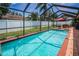 Inviting screened-in pool and outdoor living space with lush landscaping and a privacy fence at 1281 Amberlea E Dr, Dunedin, FL 34698