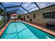 Sparkling pool enclosed in screened lanai with brick trim and outdoor seating area at 1281 Amberlea E Dr, Dunedin, FL 34698