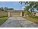 Inviting single-level home featuring a spacious driveway, a two-car garage, and a well-maintained lawn with trees at 13750 Fareham Rd, Odessa, FL 33556