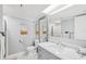 Well-lit bathroom with marble vanity, sink and a large mirror with a view to the shower at 14401 Gulf Blvd # 106, Madeira Beach, FL 33708