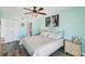 Spacious bedroom featuring laminate flooring, ceiling fan, beach artwork and ensuite bathroom at 14401 Gulf Blvd # 106, Madeira Beach, FL 33708