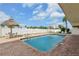 Relaxing community pool area with lounge chairs and tiki umbrella surrounded by a white fence and lush greenery at 14401 Gulf Blvd # 106, Madeira Beach, FL 33708