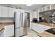 Spacious kitchen with stainless steel refrigerator, white cabinets, granite counters, and seamless flow to a dining area at 1633 Bentwood Dr, Sun City Center, FL 33573