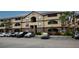 Three-story building featuring tan stucco, brown trim, screened-in balconies, palm trees, and parking at 16431 Enclave Village Dr # 16431, Tampa, FL 33647