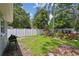 Spacious backyard with a well-maintained lawn, white fence, tropical plants, and a barbecue grill at 1817 West Dr, Clearwater, FL 33755